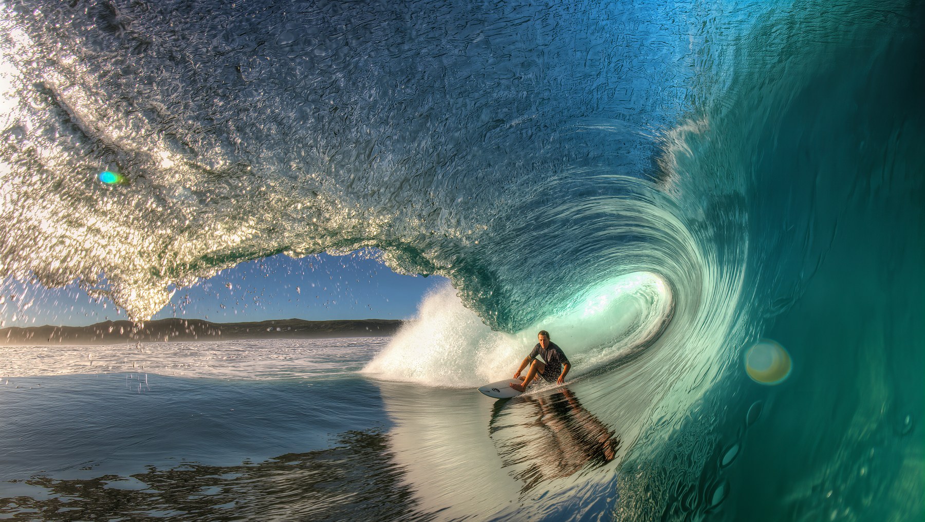 Surfer inside a breaking turquoise wave.